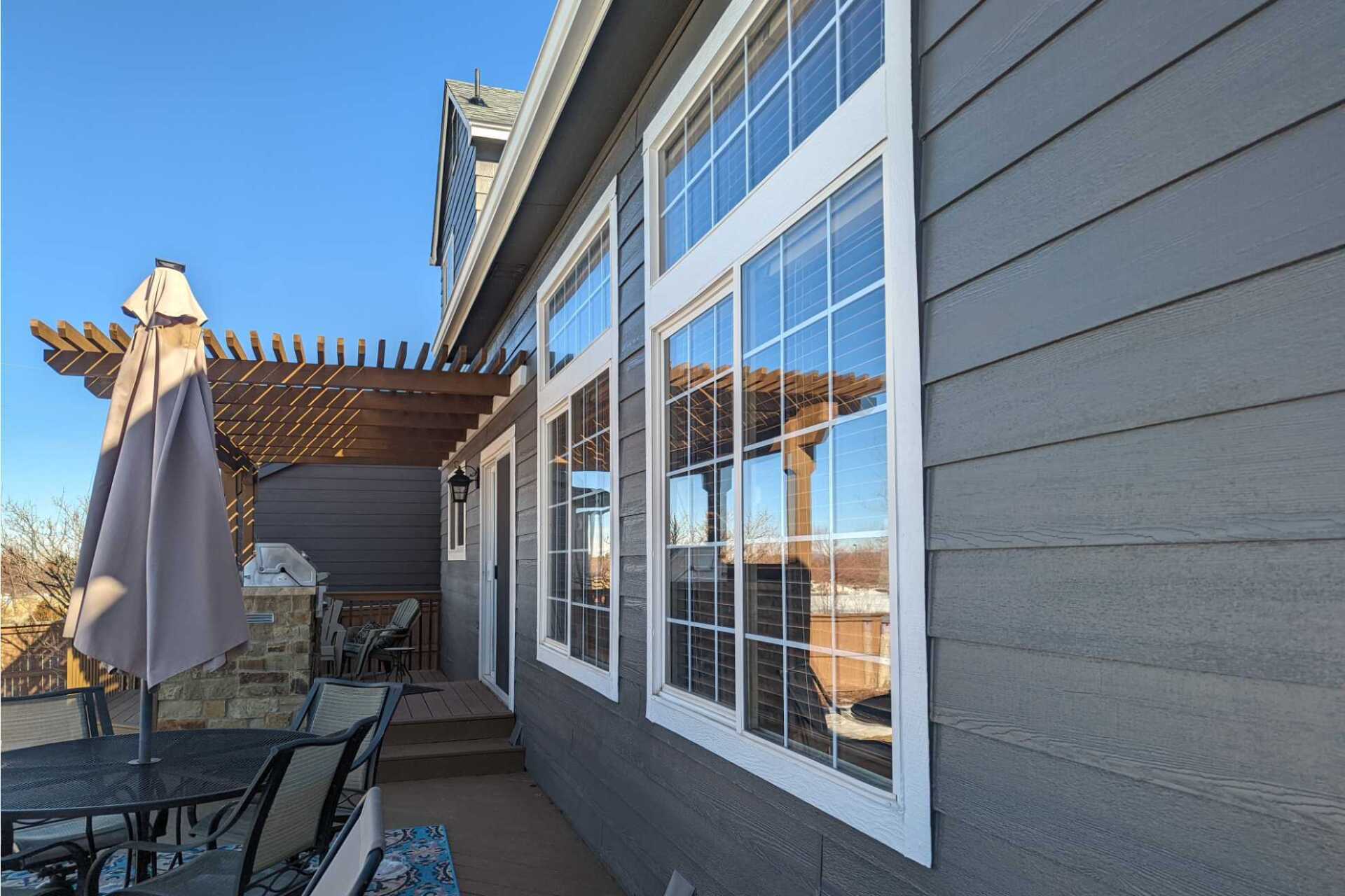 A house with a lot of windows and a patio with a table and chairs.