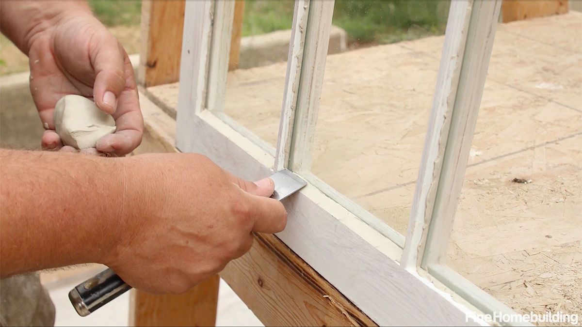A man is working on a window with a spatula.