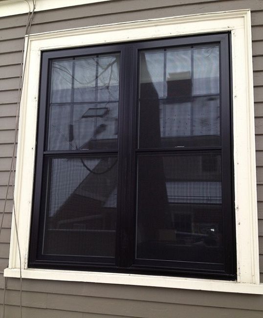 A black window with a white trim sits on the side of a house