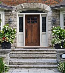 The front door of a brick house with a wooden door and steps.