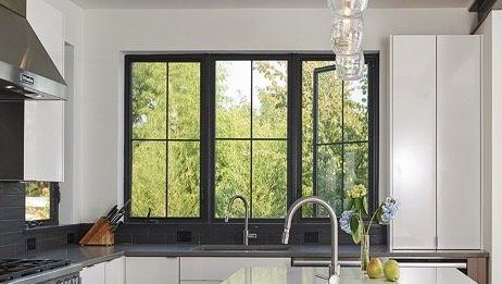 A kitchen with a sink , stove , and three windows.