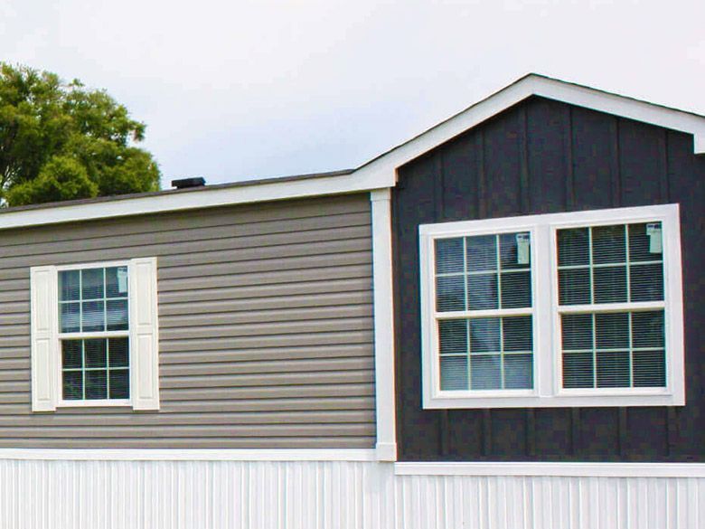 A mobile home with two windows on the side of it