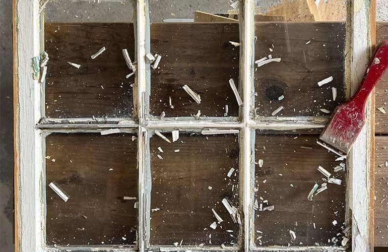 A window is being painted with a brush on a wooden table.