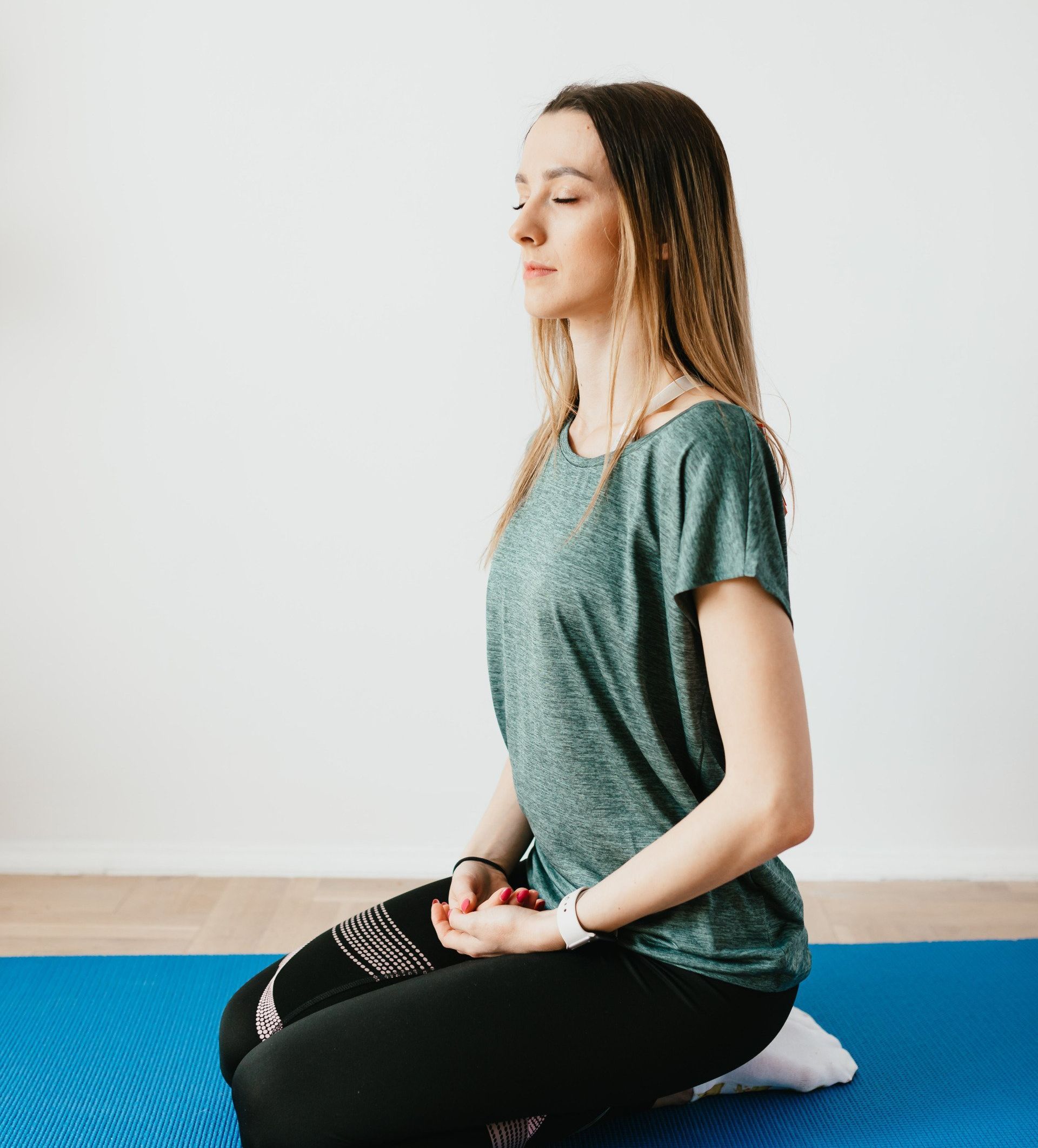 a woman is sitting on a yoga mat with her eyes closed .