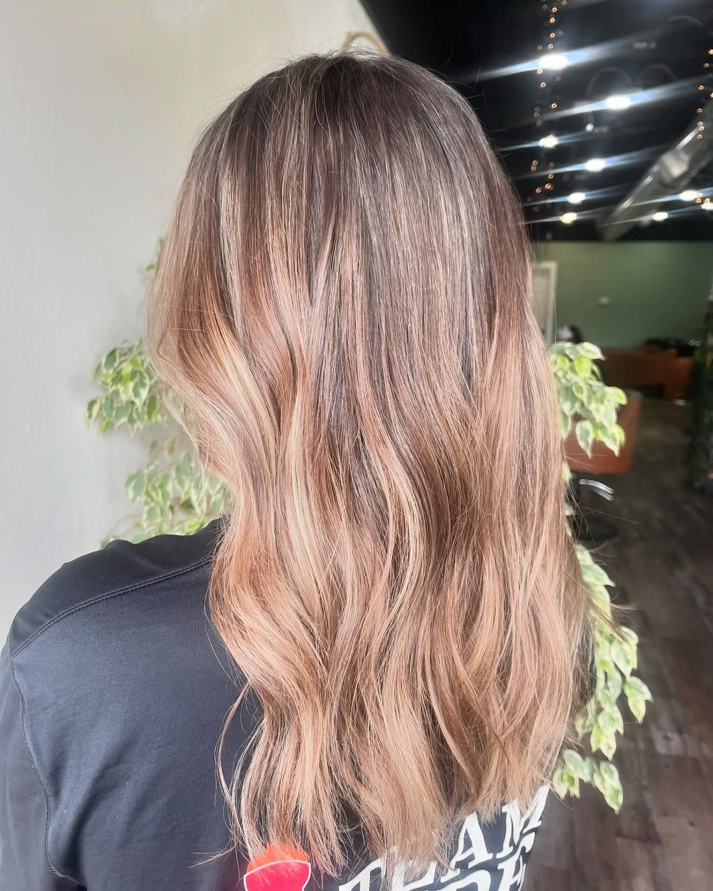 Woman with ombre wavy hair, dark roots fading to light brown ends.