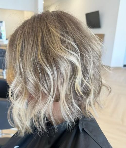 Blonde, wavy bob haircut with lighter highlights.