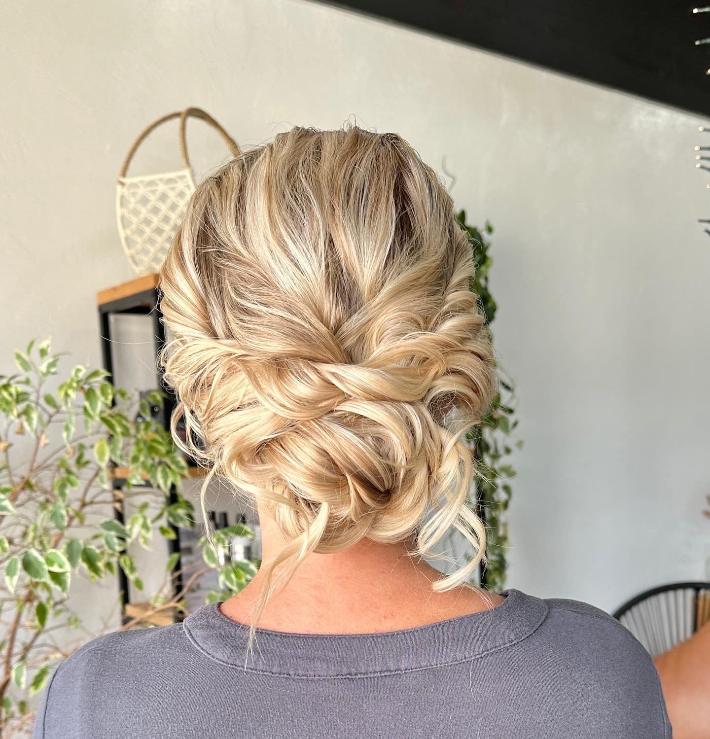 Woman with blonde, updo hairstyle. Back view, indoors, gray shirt.