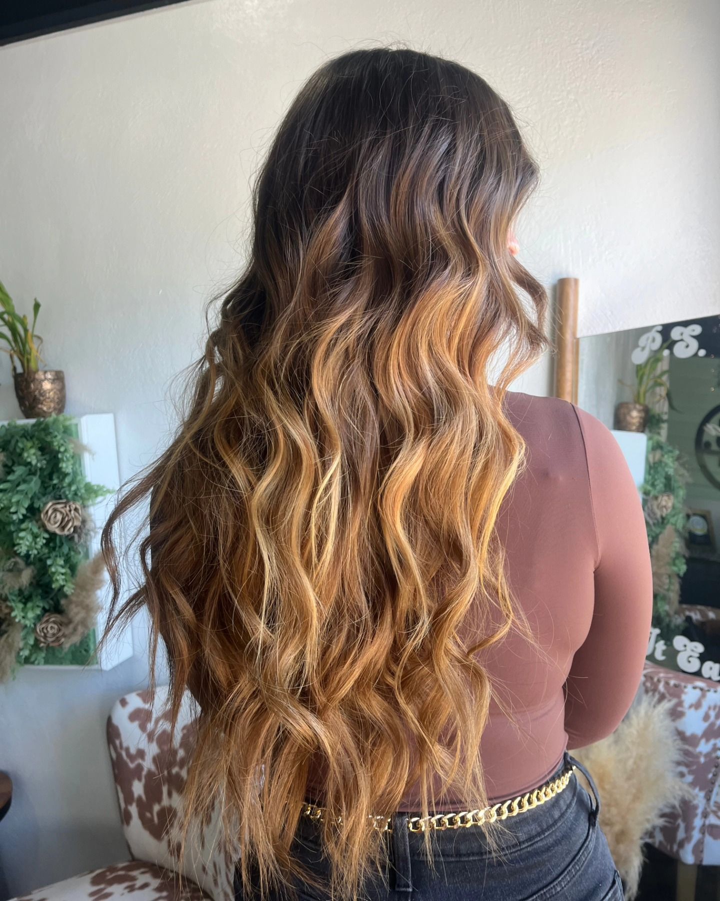 Woman with long wavy hair in brown to blonde ombre.