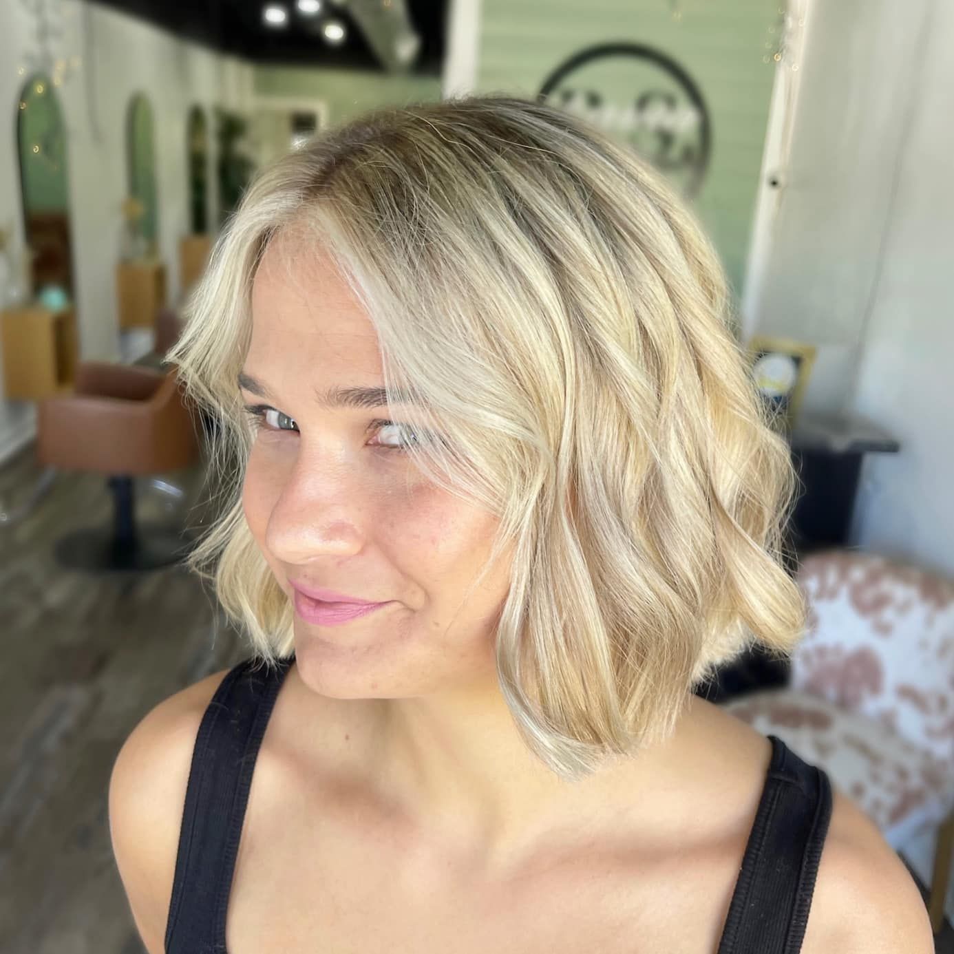 Woman with layered, wavy blonde bob in salon setting.