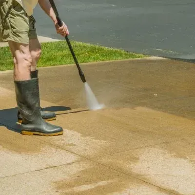 Pressure washing a concrete driveway to remove surface dirt during an exterior clean in Highcliff, Dunedin.