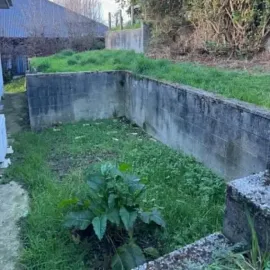 Before: Overgrown lawn and vegetation around retaining walls at a Kaikorai, Dunedin property.