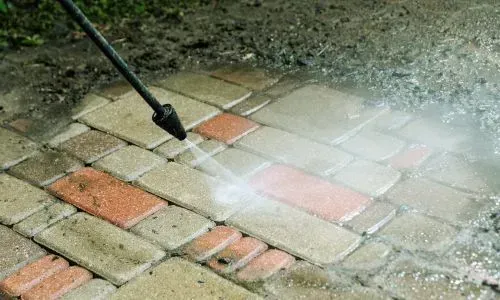 Pressure washing paver patio to remove grime and restore surface colour during residential water blasting in Dunedin.