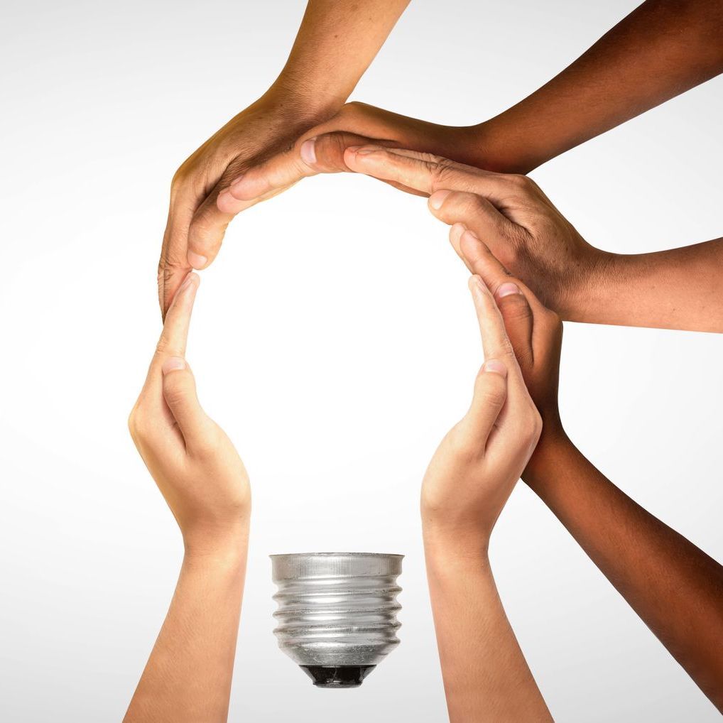 A group of people holding a light bulb in their hands