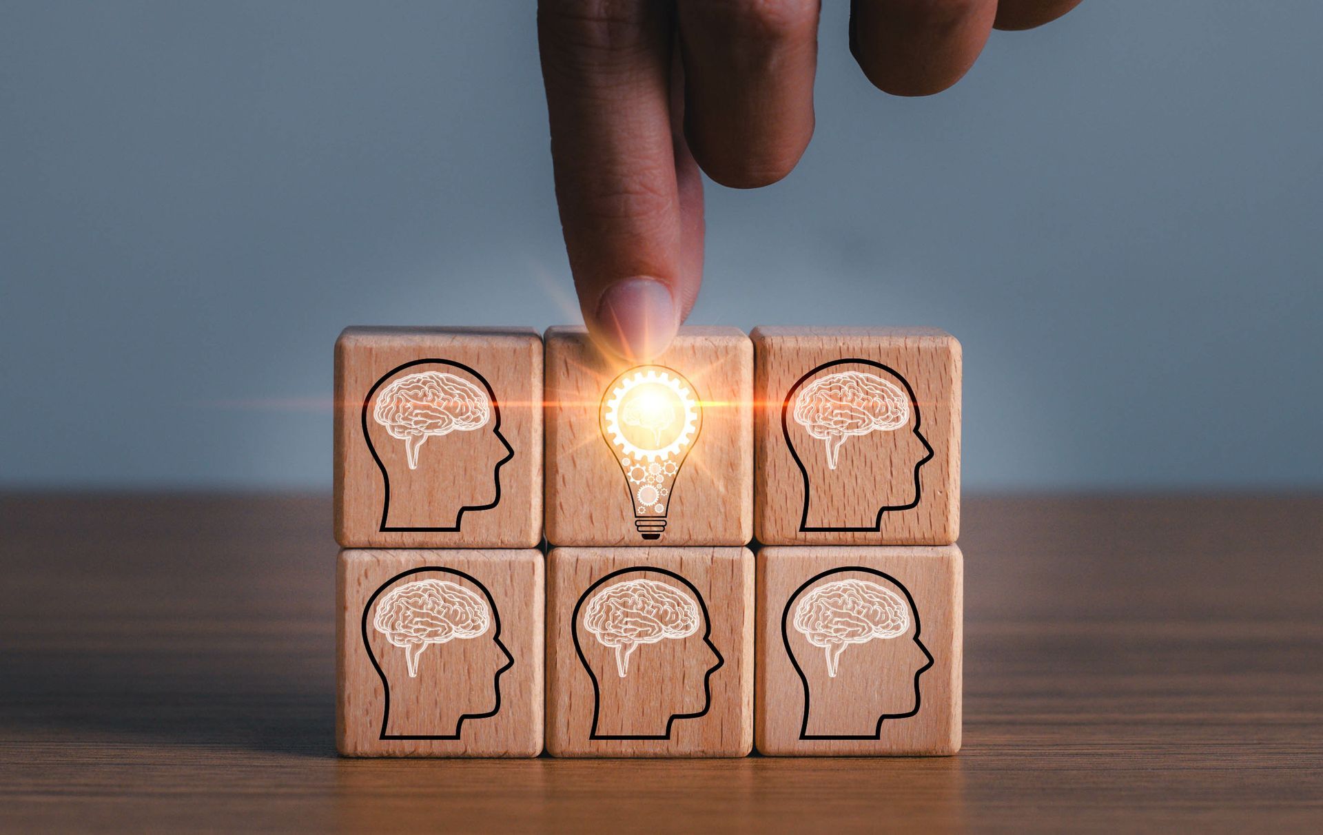 A hand is pushing a wooden block with a light bulb on it