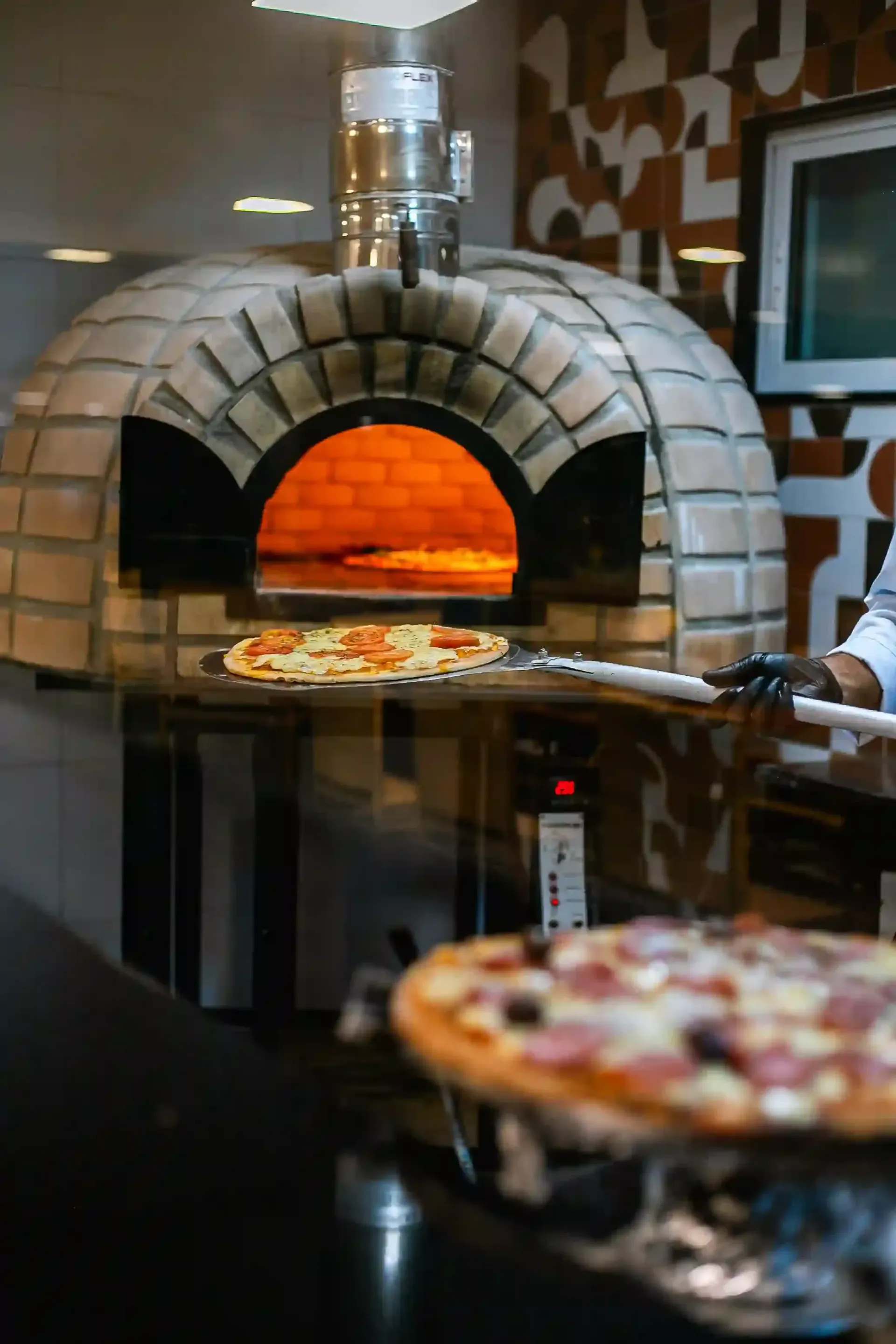 Um forno de pizza está sendo usado para assar uma pizza em um restaurante.-hotel-praia-dourada-maragogi-park