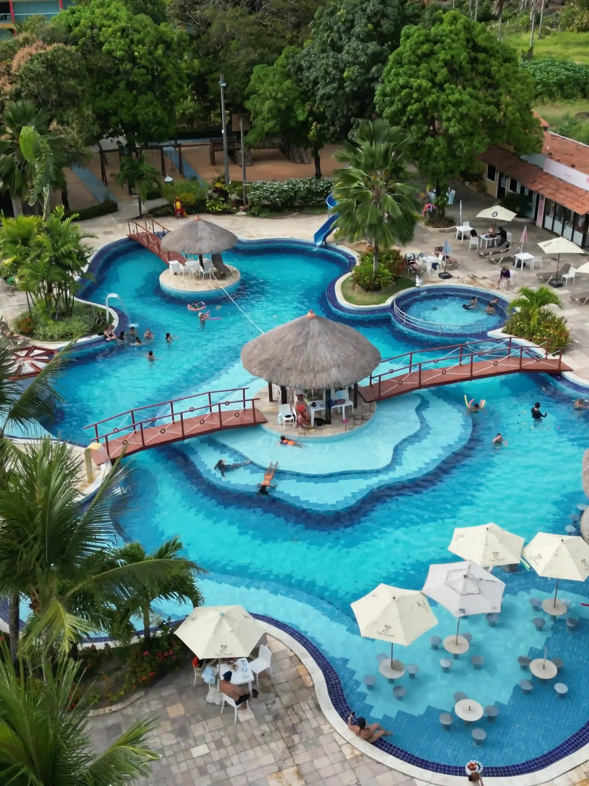 Uma vista aérea de uma grande piscina cercada por palmeiras.-hotel-praia-dourada-maragogi-park