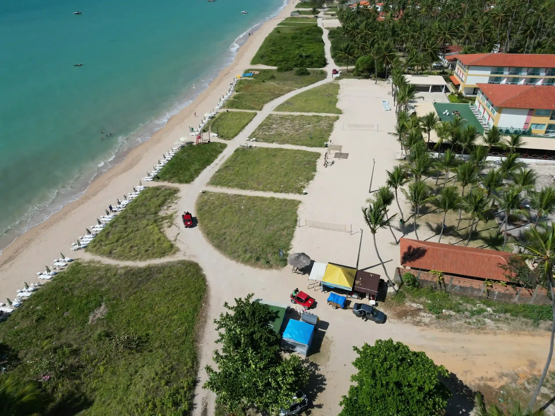 Uma vista aérea de uma praia com palmeiras e uma estrada que leva até ela.-Hotel-Praia-Dourada-Maragogi-Park