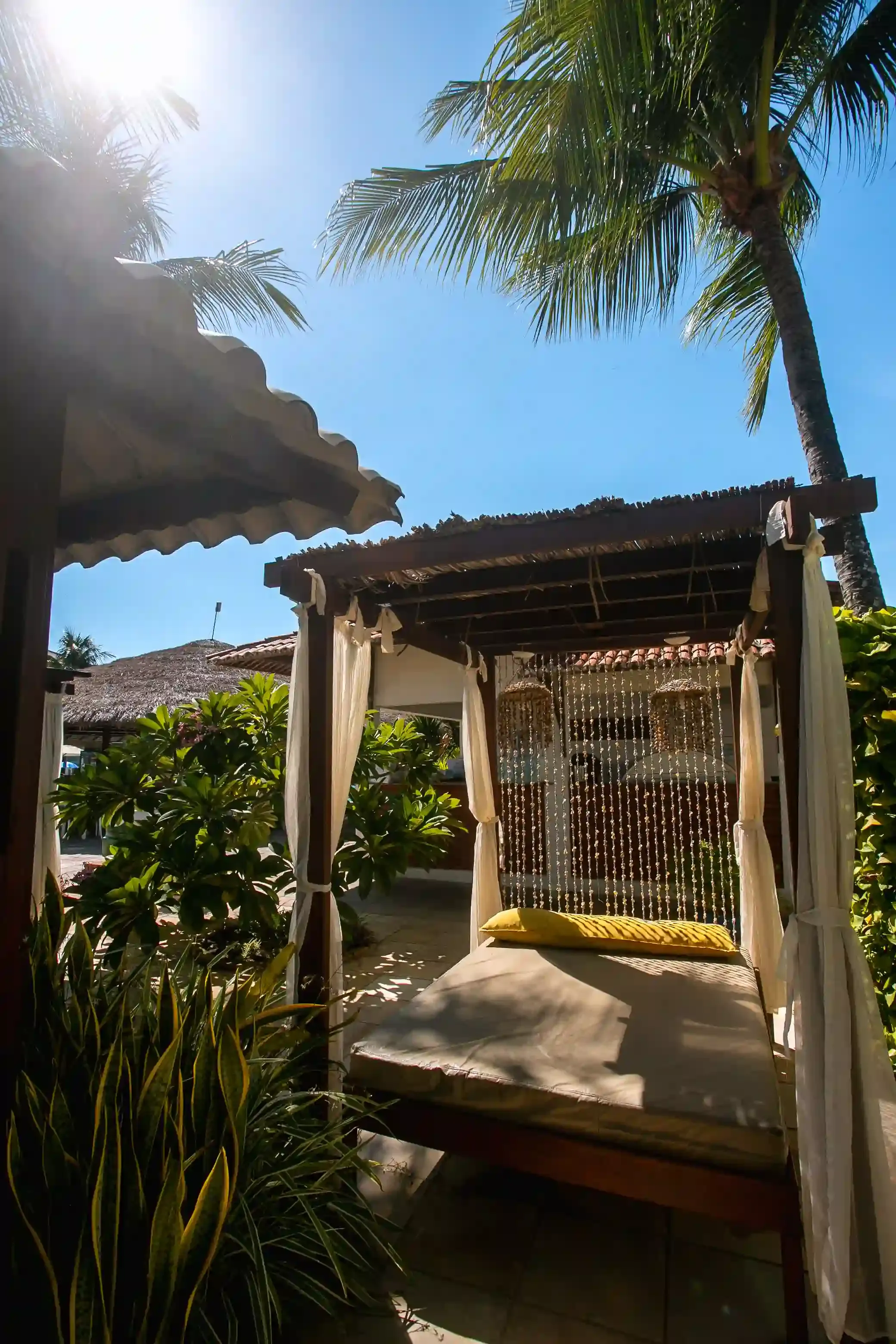 Uma cama sob um dossel com uma palmeira ao fundo.-Hotel-Praia-Dourada-Maragogi-Park