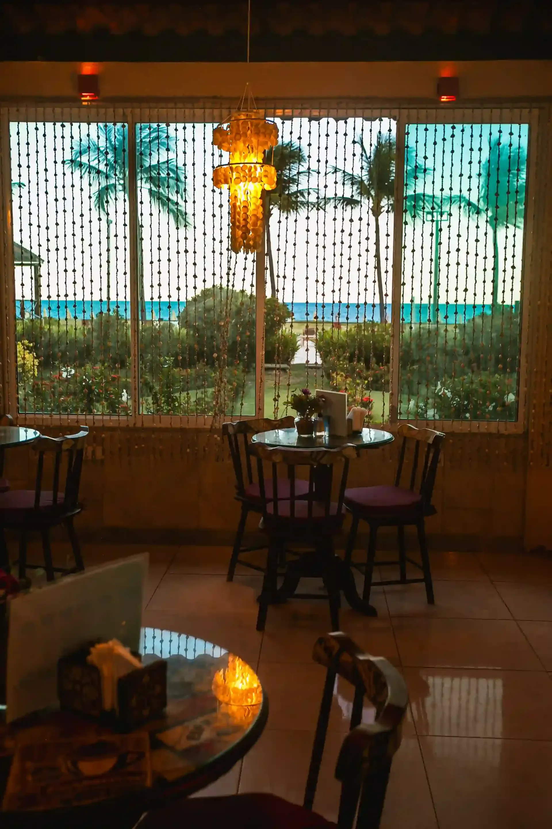 Um restaurante com mesas e cadeiras e uma grande janela com vista para o oceano.-Hotel-Praia-Dourada-Maragogi-Park