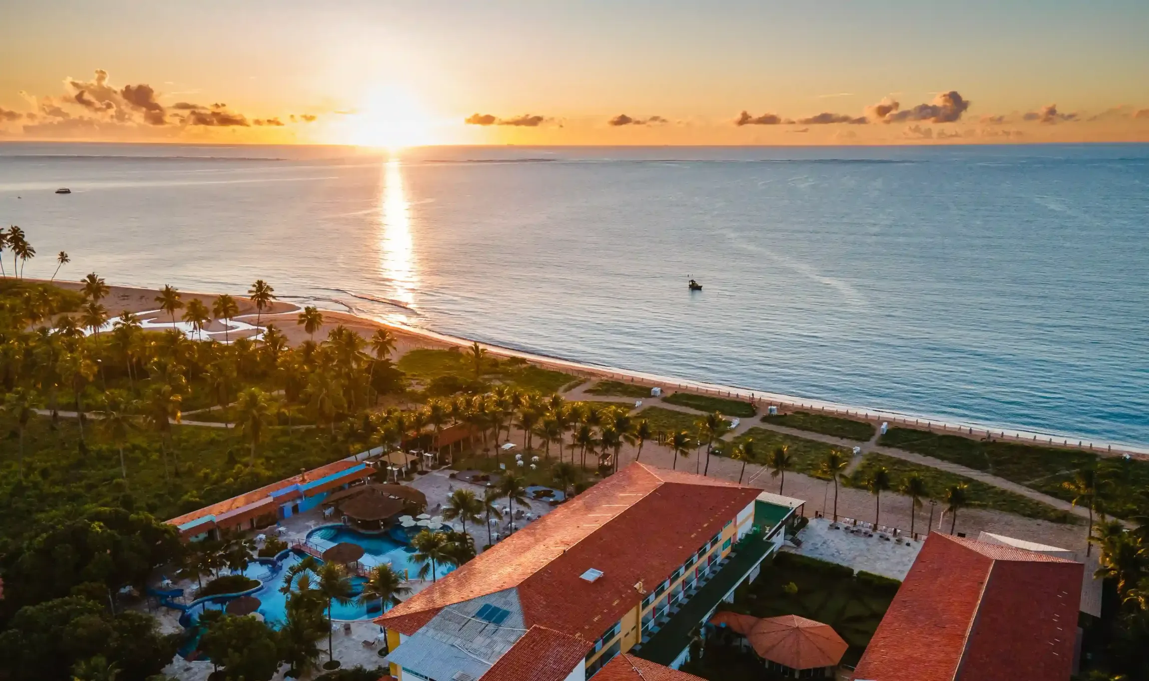 Uma vista aérea de um resort de praia ao pôr do sol.-hotel-praia-dourada-maragogi-park