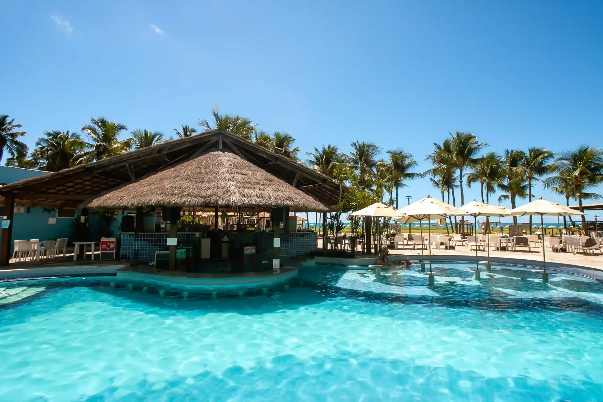 Uma grande piscina com um bar no meio-Hotel-Praia-Dourada-Maragogi-Park
