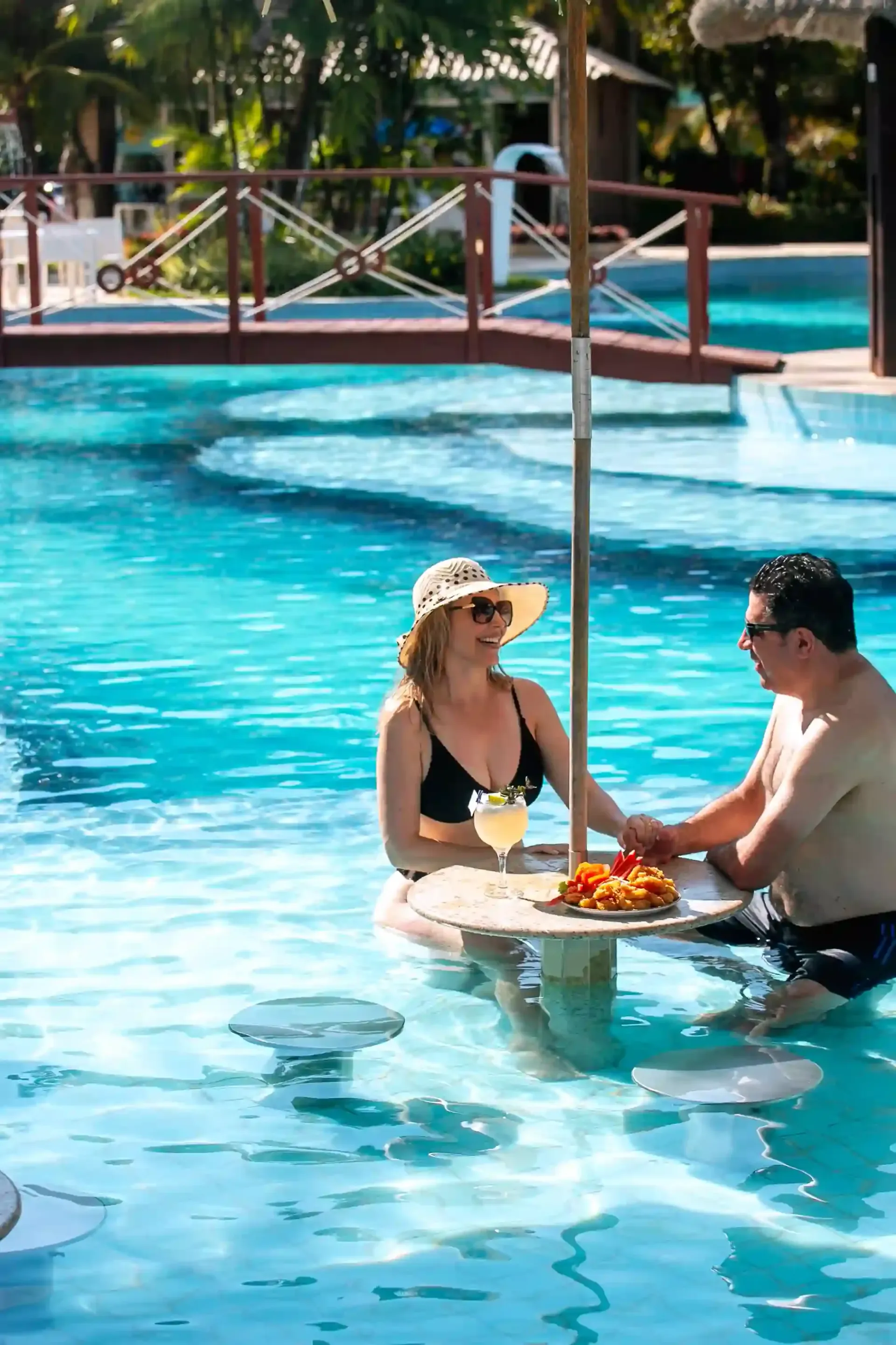 Um homem e uma mulher estão sentados à mesa em uma piscina.-hotel-praia-dourada-maragogi-park