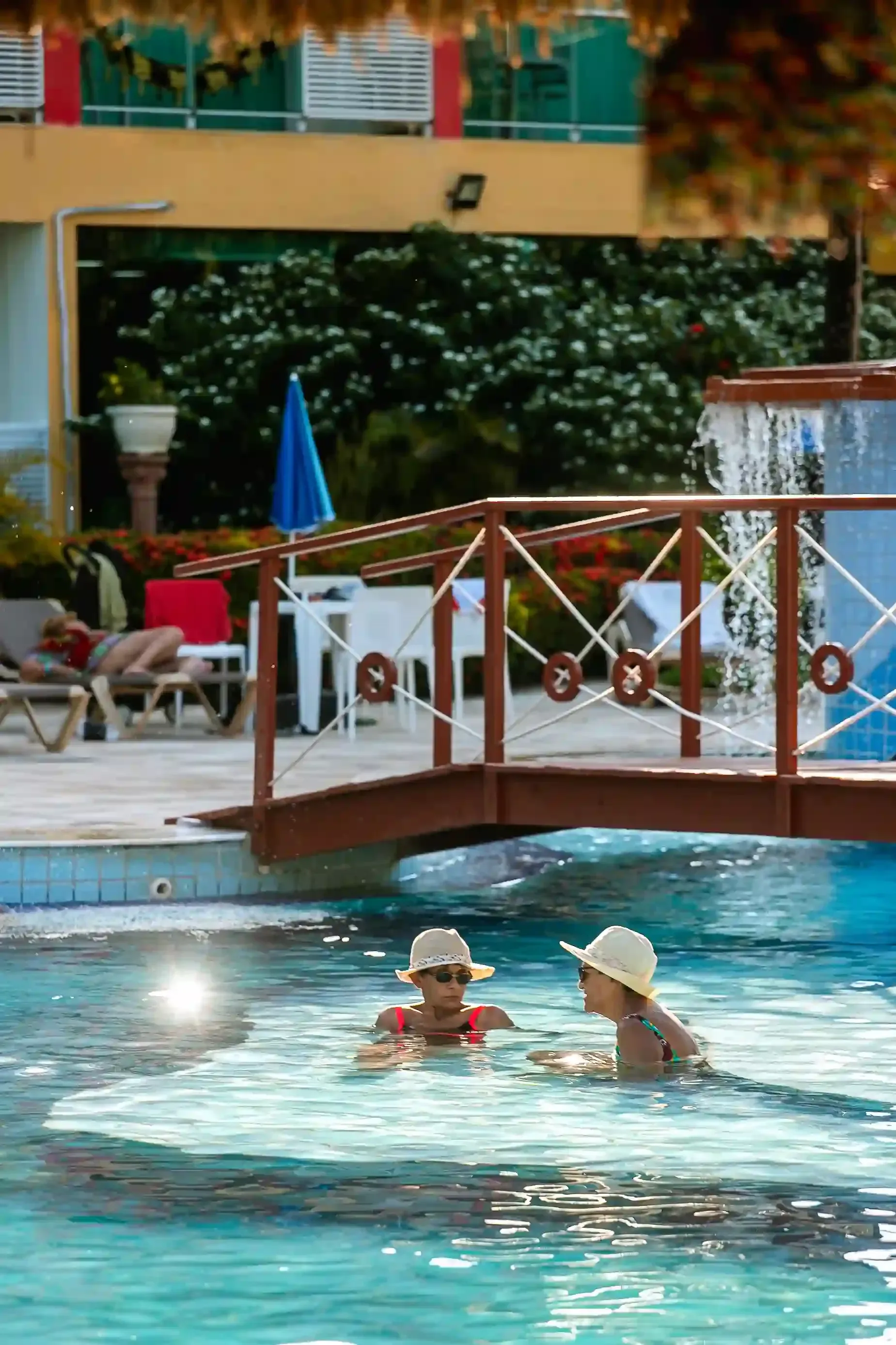 Duas pessoas estão nadando em uma piscina debaixo de uma ponte.-hotel-praia-dourada-maragogi-park