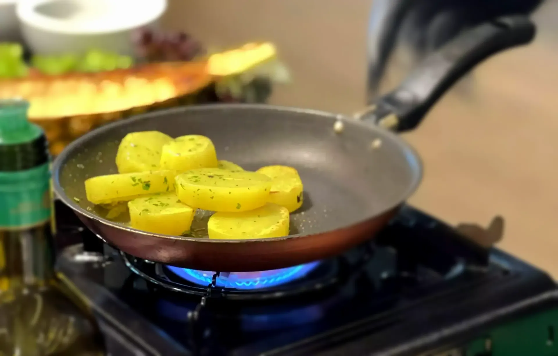 Batatas amarelas fritando em uma panela sobre a chama azul do fogão.