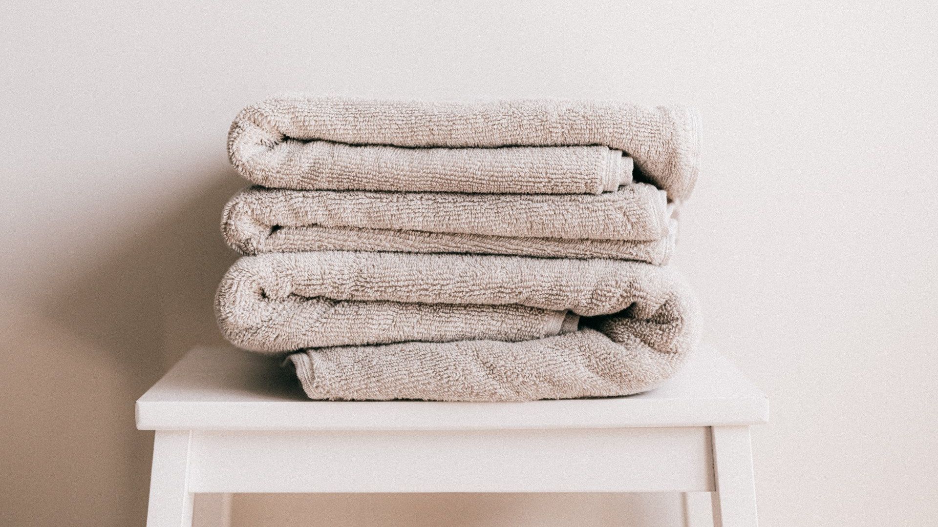 A stack of towels is sitting on top of a white stool.