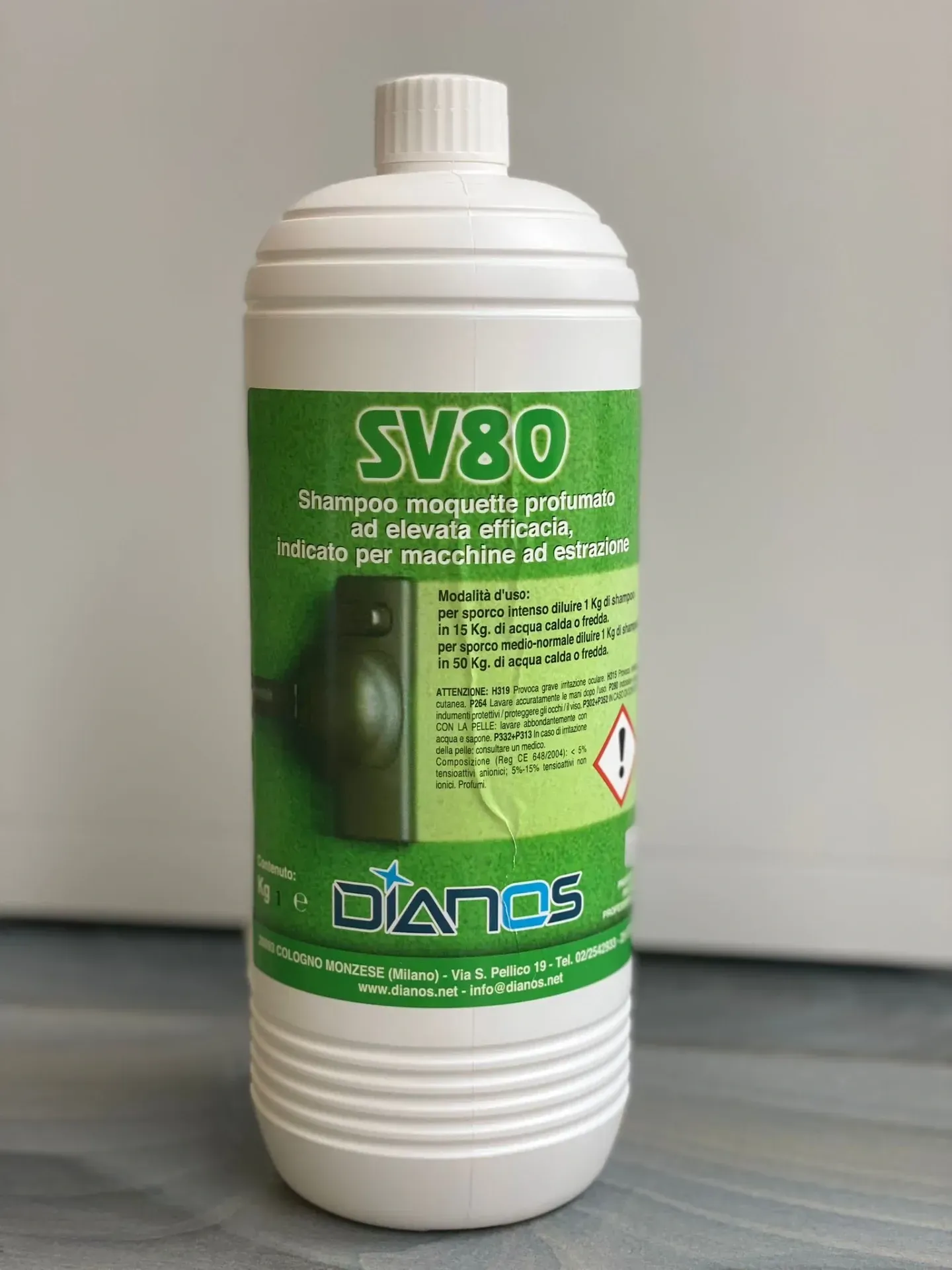 Bottiglia di plastica bianca con etichetta verde, grafica a forma di foglia e simbolo di pericolo su sfondo neutro.