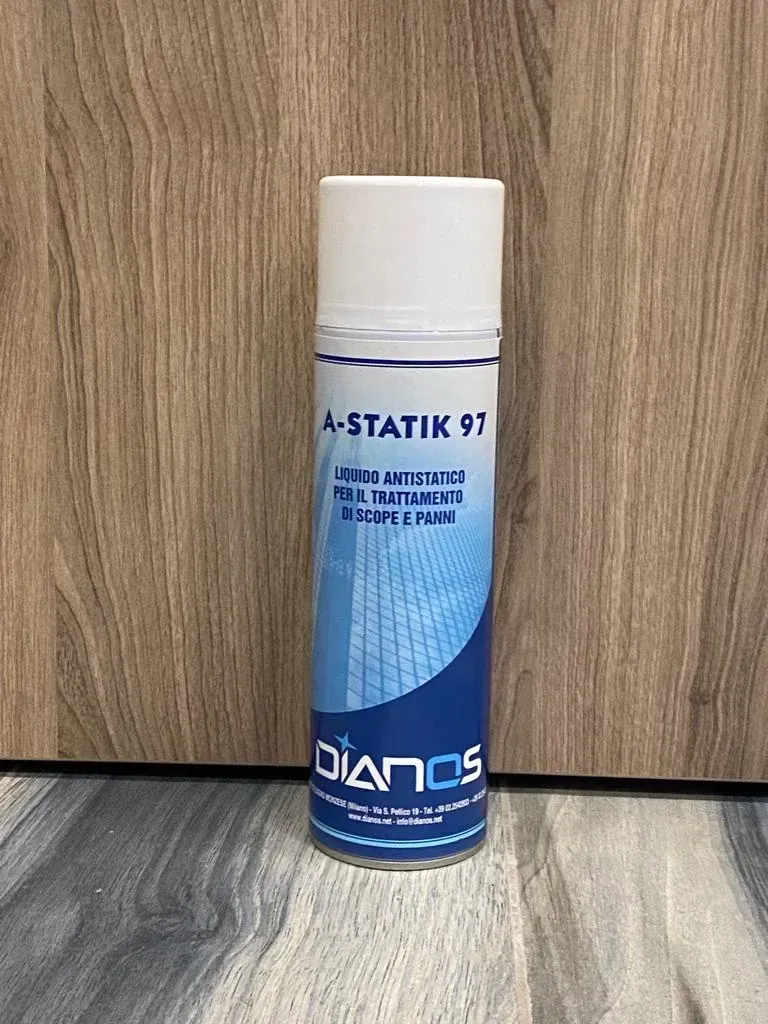 Bomboletta aerosol A-STATIK 97 blu e bianca appoggiata su un pavimento con motivo effetto legno, sullo sfondo di un pannello di legno.