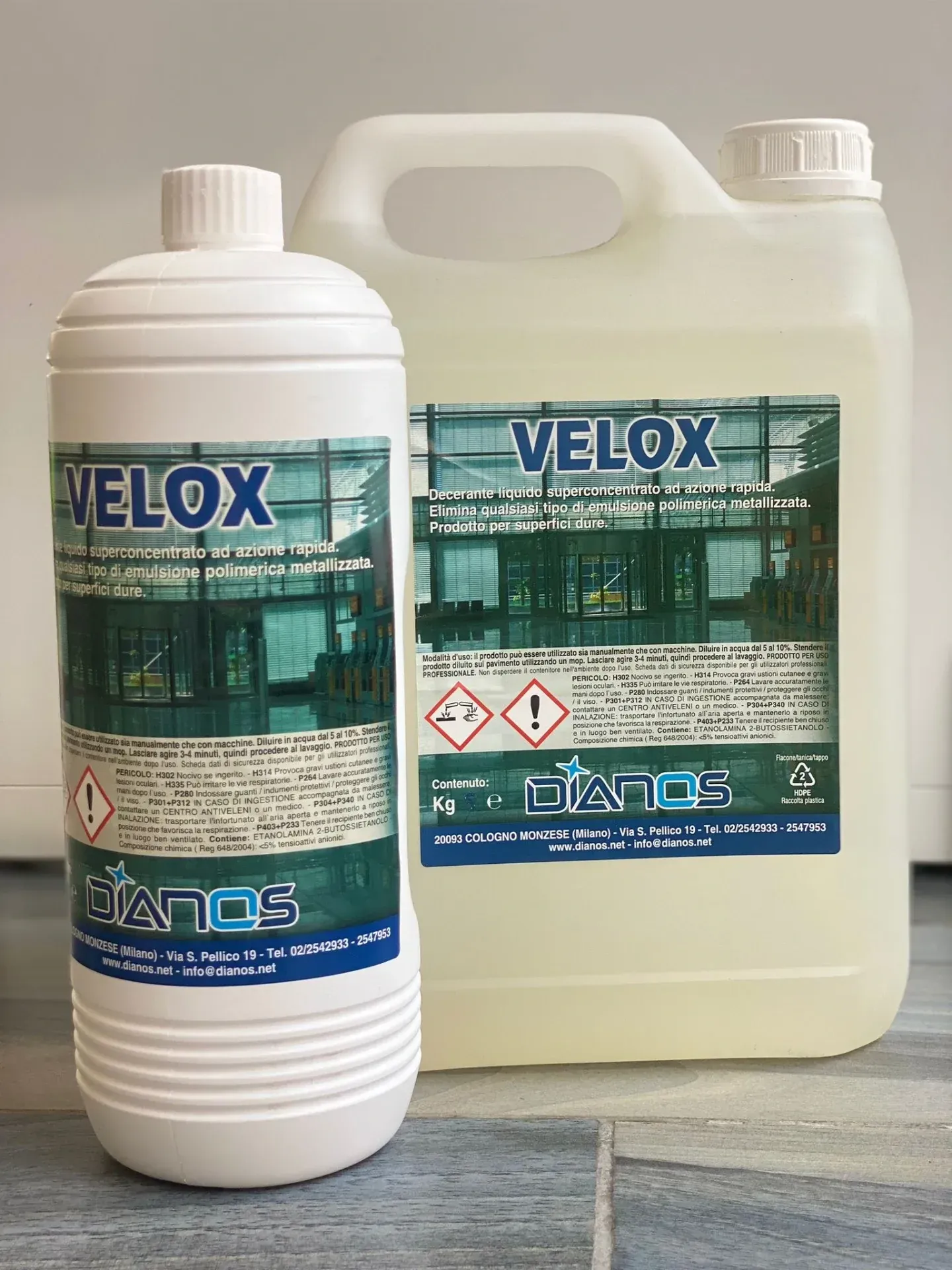 Due flaconi di detersivo VELOX, uno bianco e uno giallo traslucido, su un tavolo.