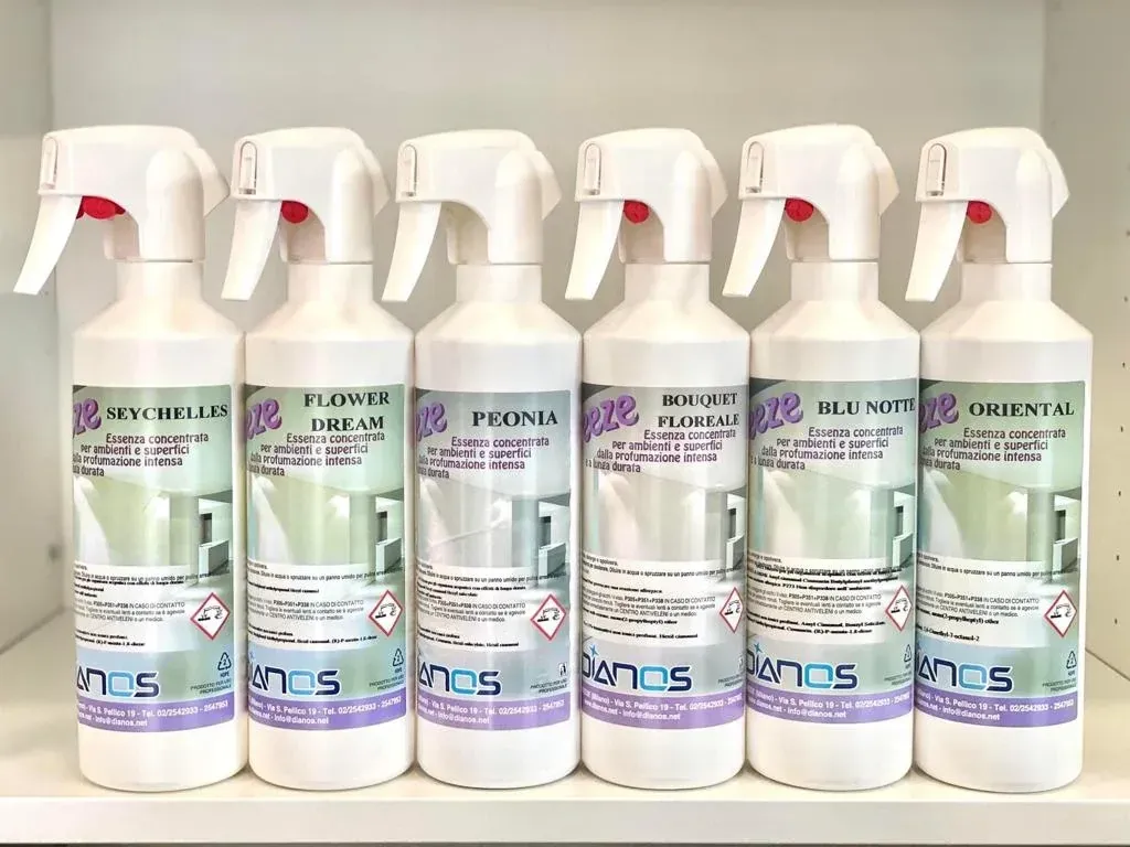 Sei flaconi spray di prodotto per la pulizia allineati su uno scaffale su uno sfondo bianco