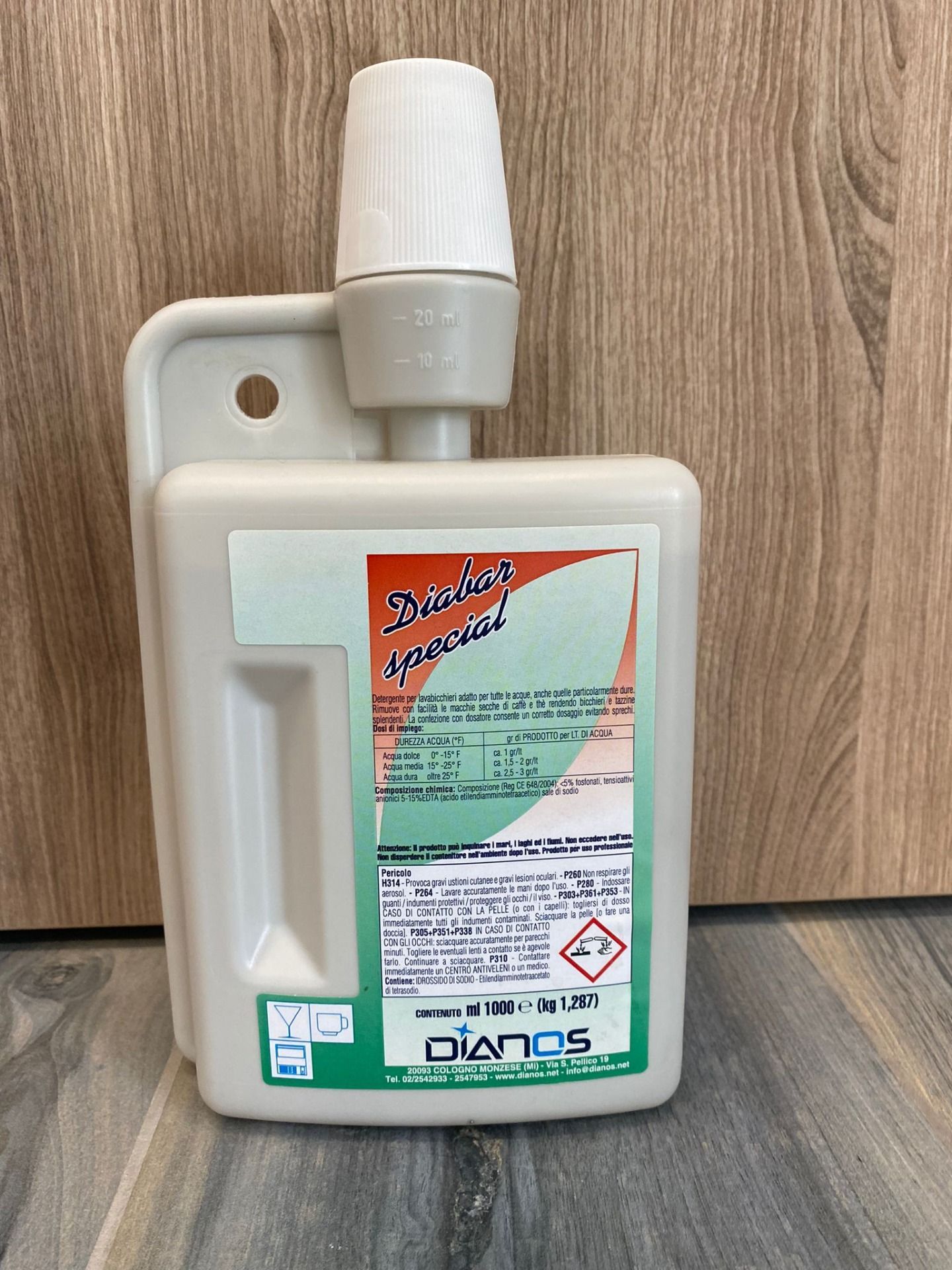 Contenitore di plastica bianca con manico e tappo, su cui è apposto un adesivo colorato di avvertenza sui prodotti chimici.