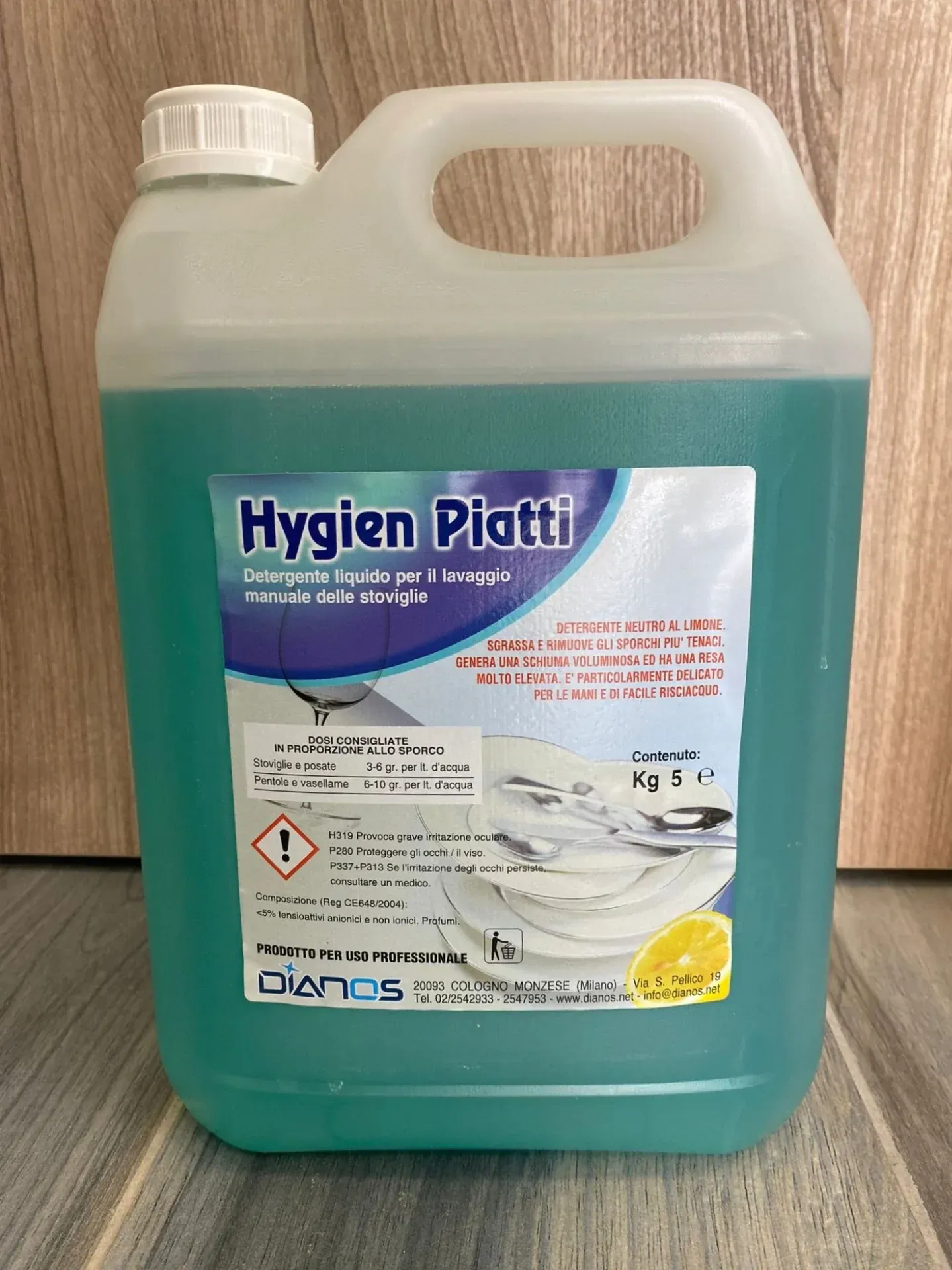 Grande flacone in plastica trasparente di colore blu-verde contenente il detergente liquido Hygien Platti, dotato di manico e tappo bianco.
