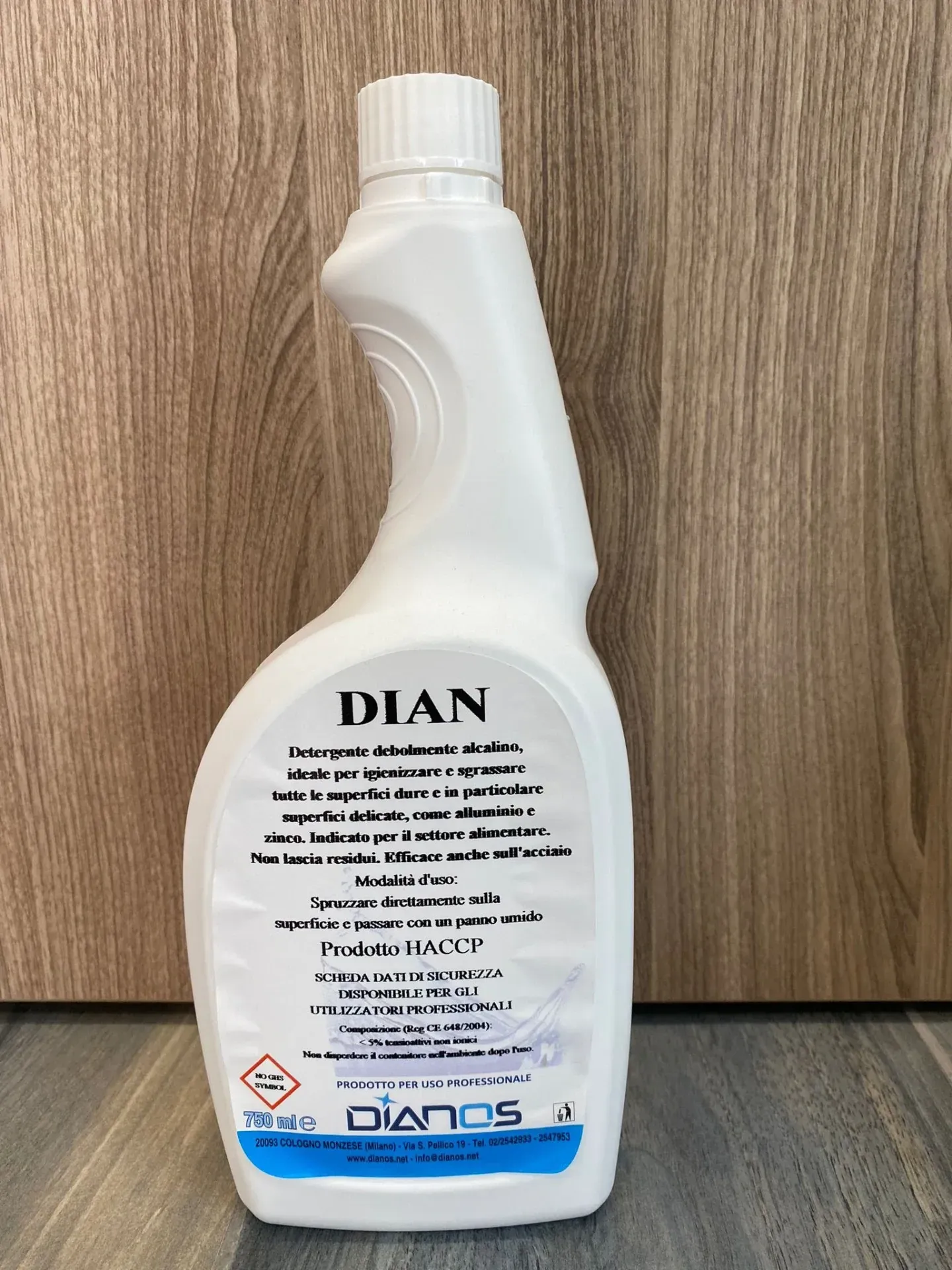 Flacone per detersivo DIAN bianco con tappo blu su una superficie in legno.