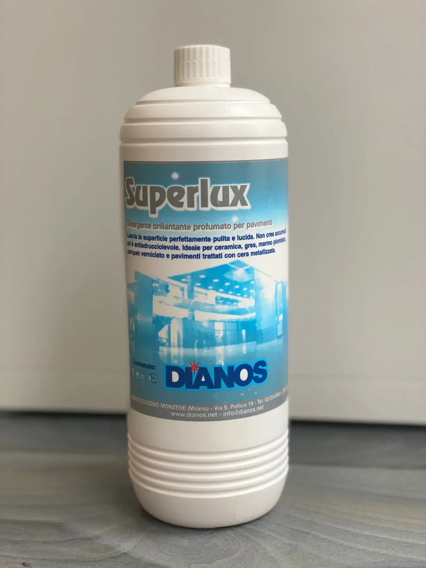 Flacone bianco del prodotto per la pulizia Superlux con etichetta blu su sfondo grigio.