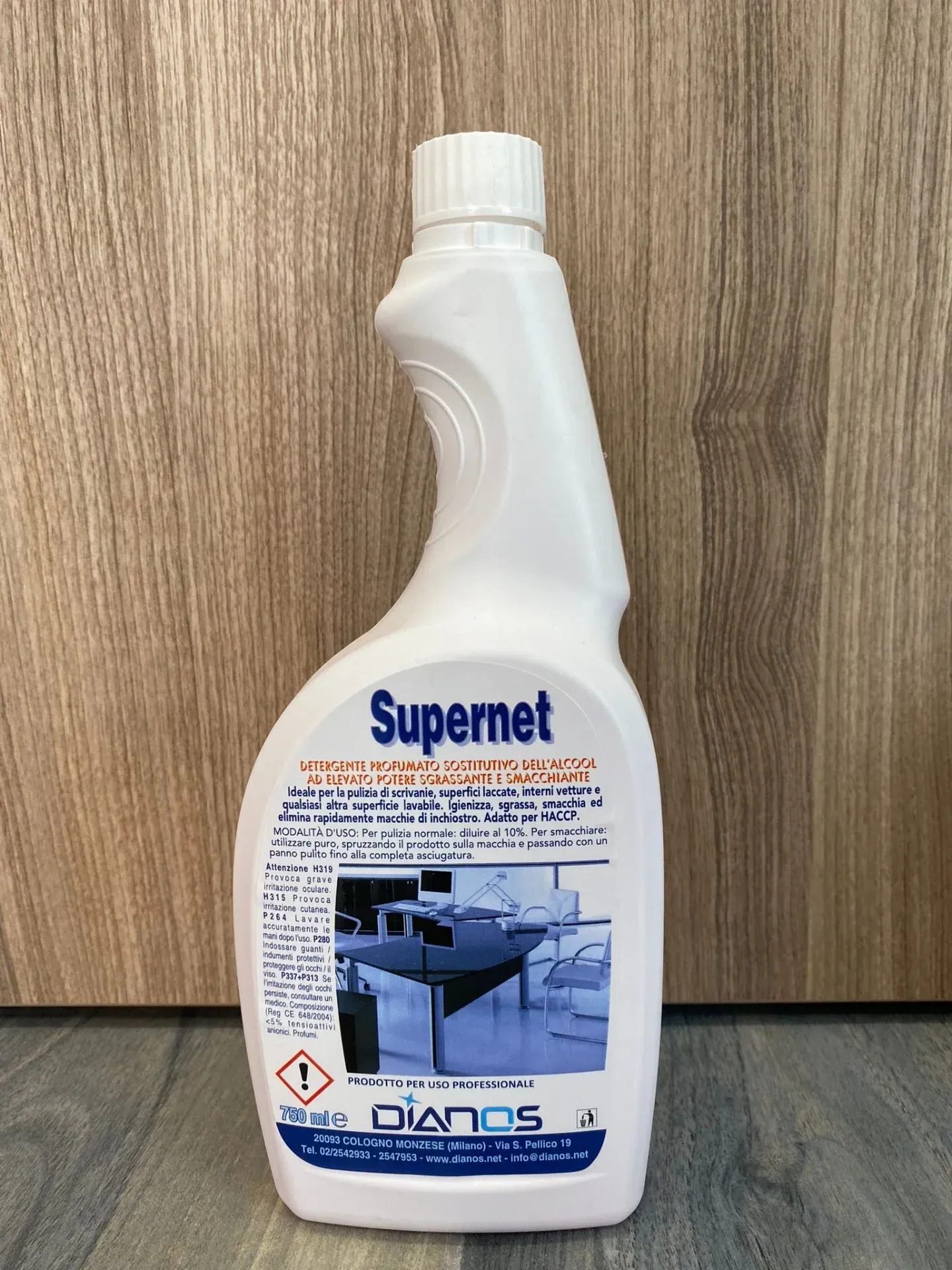 Flacone bianco di spray detergente Supernet su una superficie di legno.