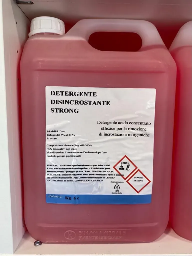 Contenitore rosa per detersivo con etichette di pericolo e tappo bianco su uno scaffale