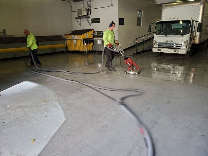 A person in a harness stands in an aerial lift, using a squeegee to clean the glass facade of a building. A person in a harness stands in an aerial lift, using a squeegee to clean the glass facade of a building.