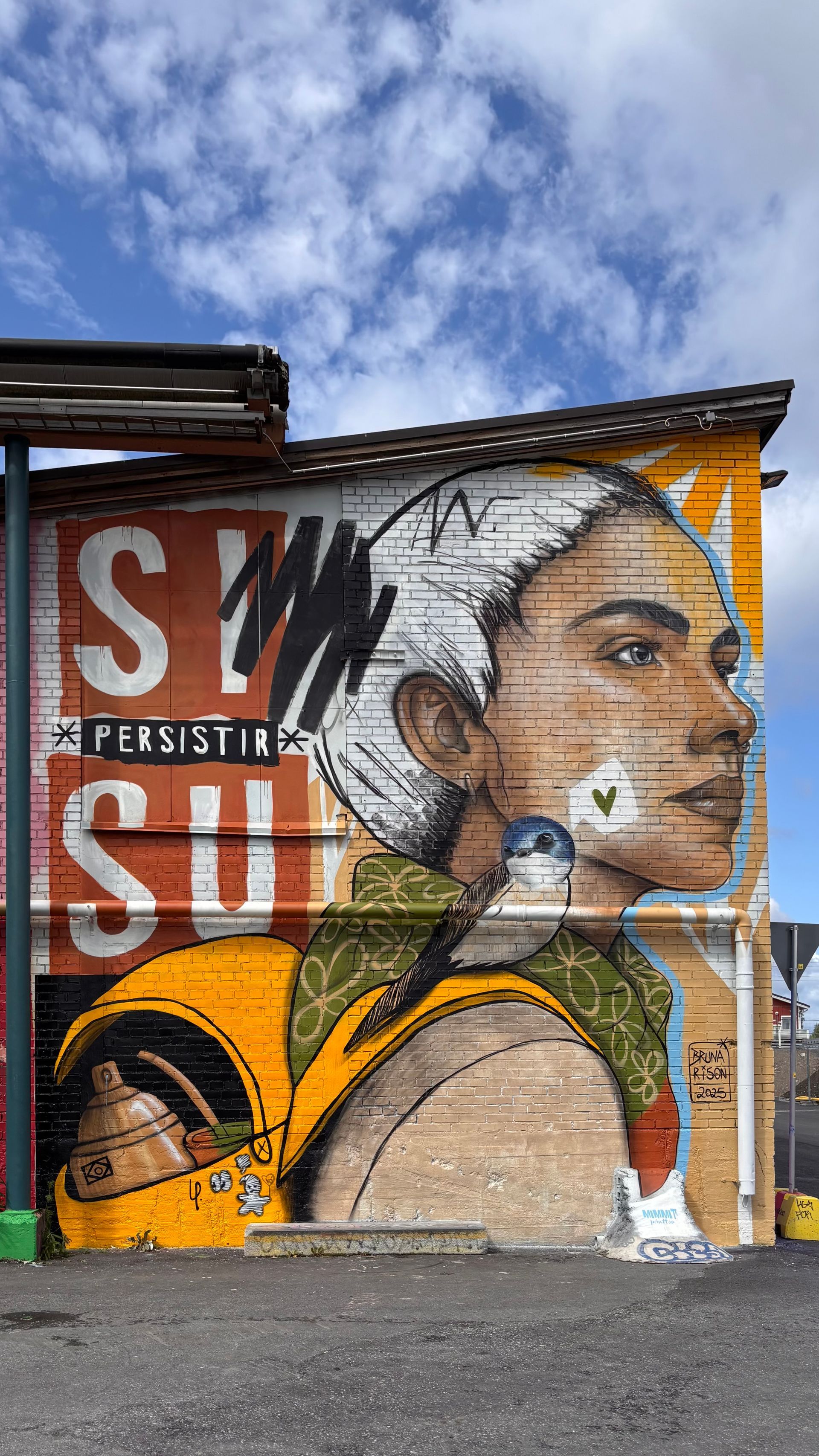 Mural em muro de paredede rodoviária com figuras feminina se abraçando.