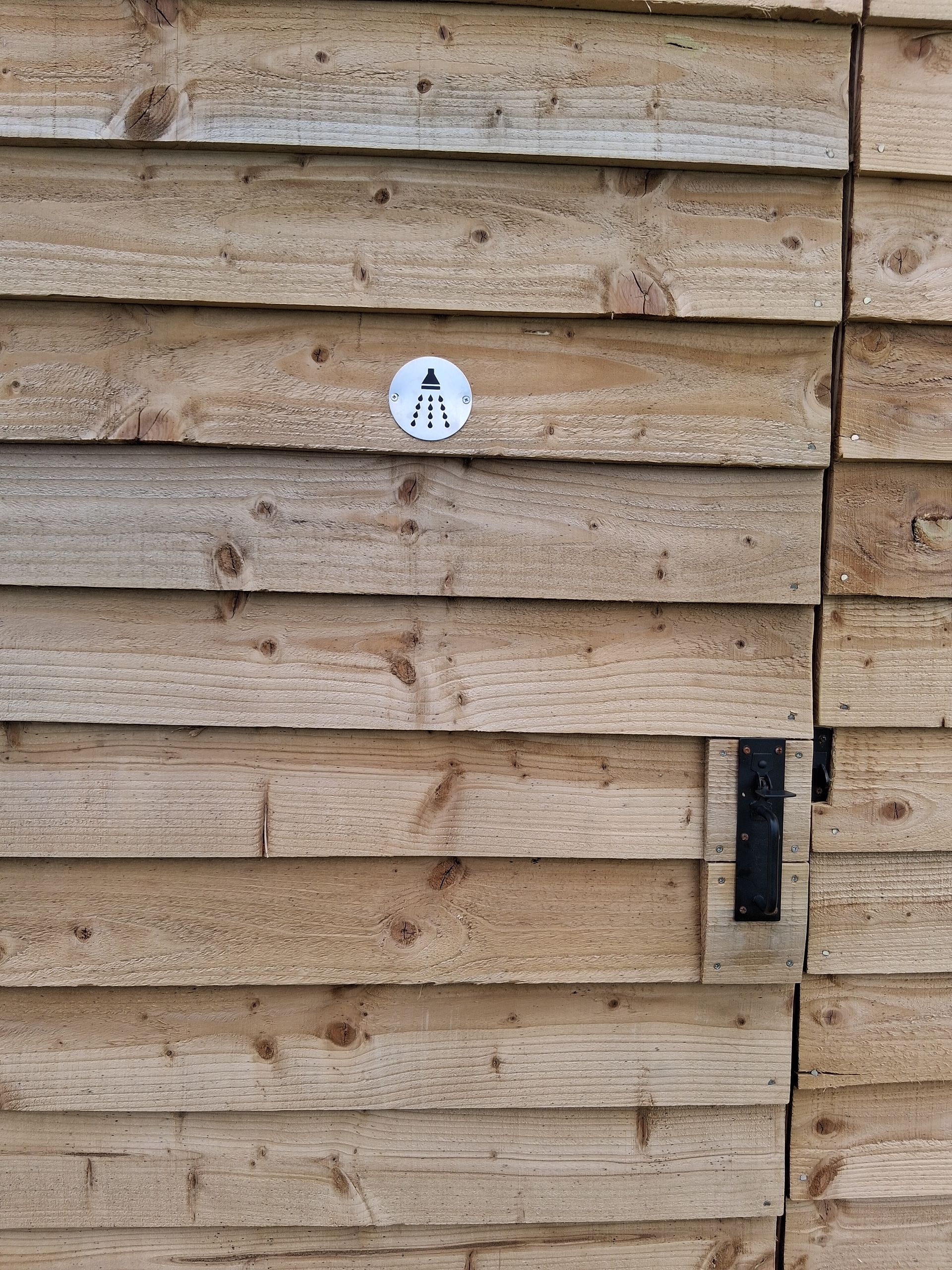 Wooden fence with a small round sign and a black latch on the right side