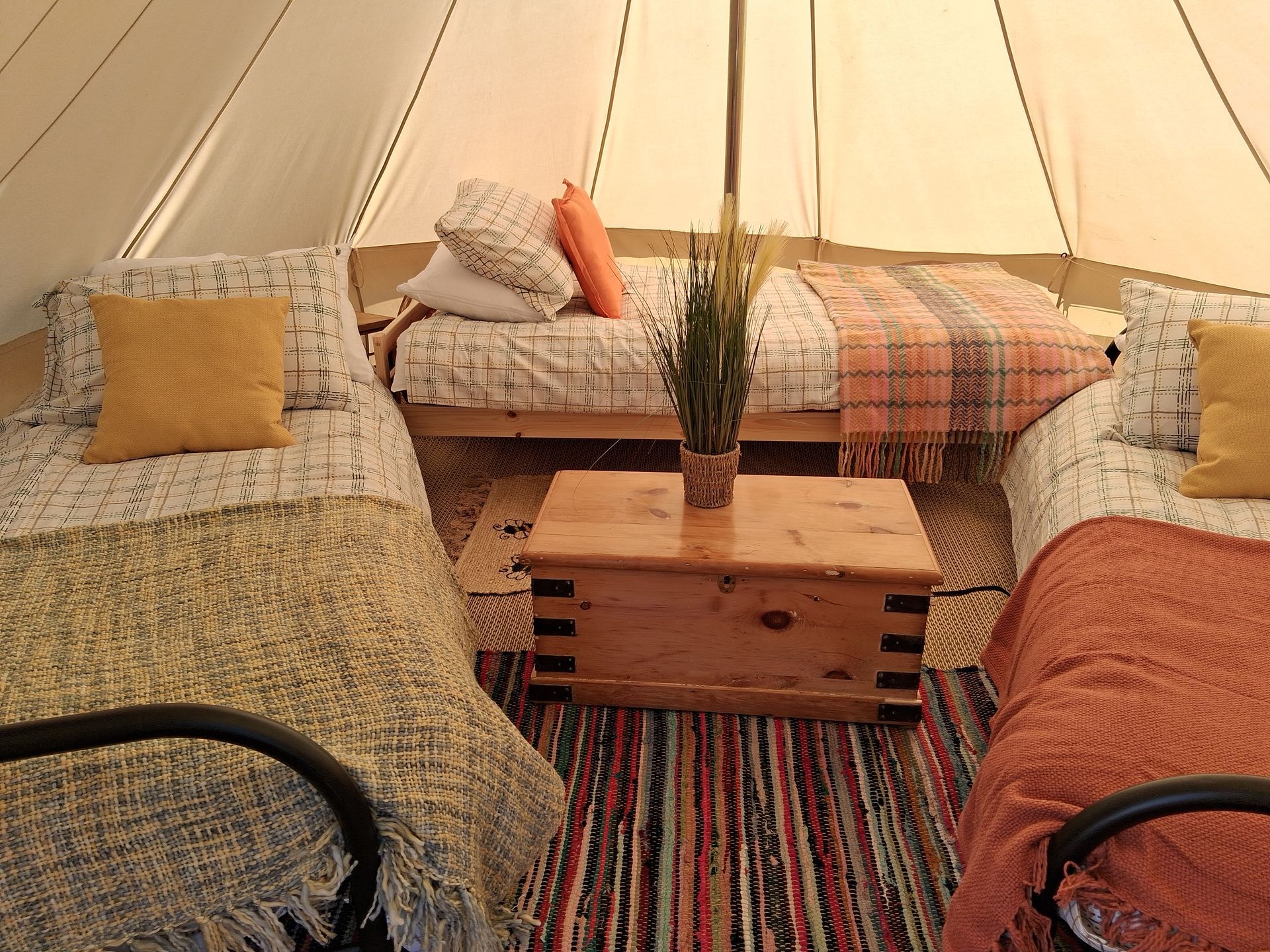 Cozy tent lounge with patterned cushions, low wooden table, striped rug, and warm lighting