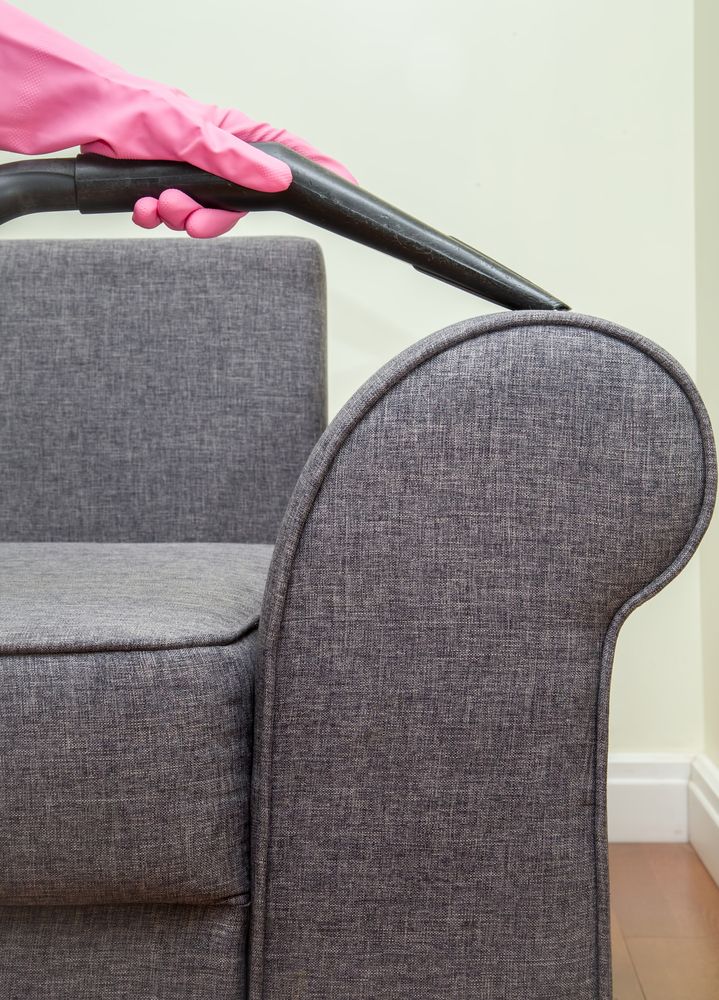 A Person is Cleaning a Grey Couch With Vacuum Cleaner — We Clean Lounges In Beerwah, QLD