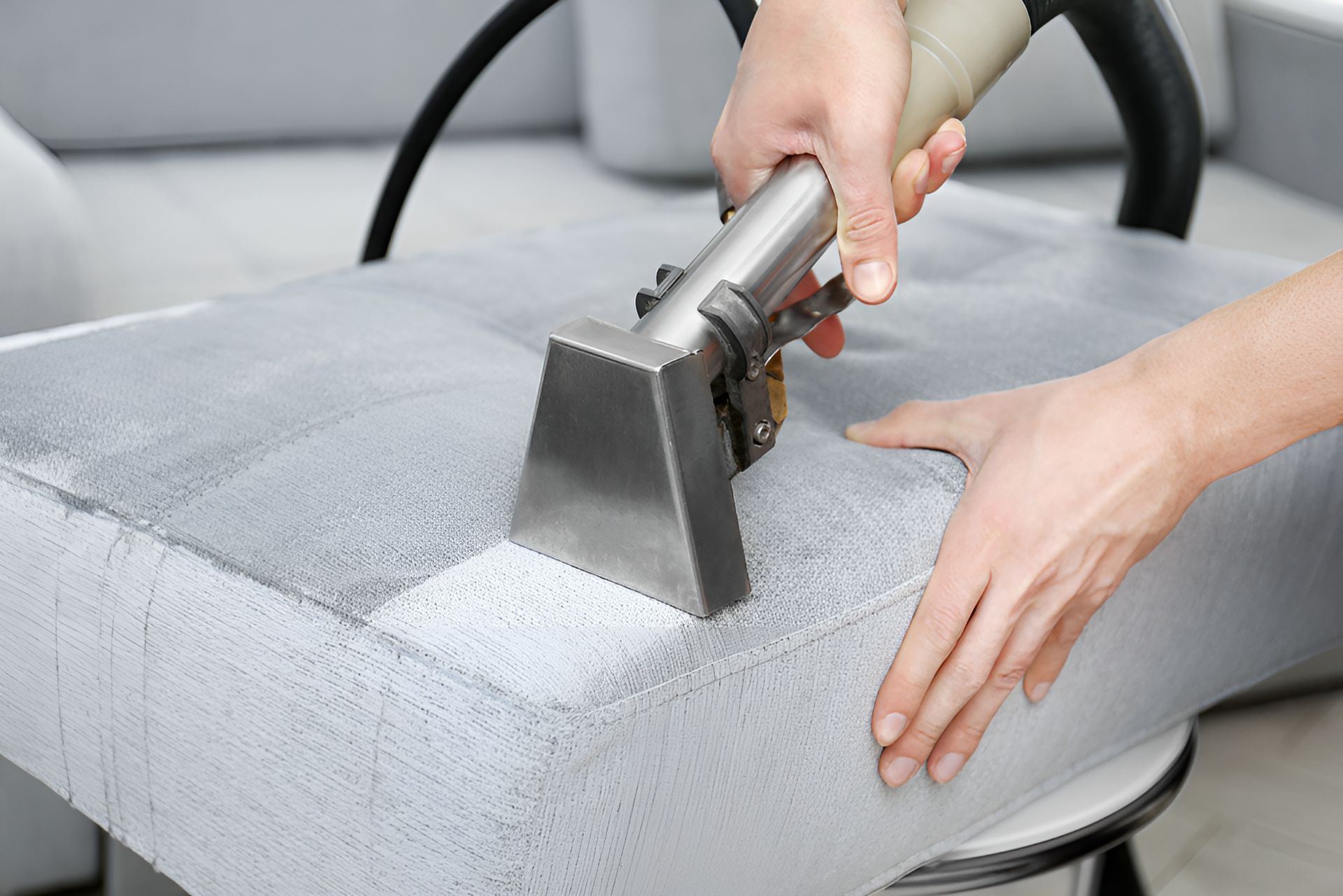 A person is cleaning a couch with a vacuum cleaner. — We Clean Lounges In Maroochydore, QLD