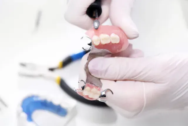 a person wearing gloves is holding a denture in their hand .