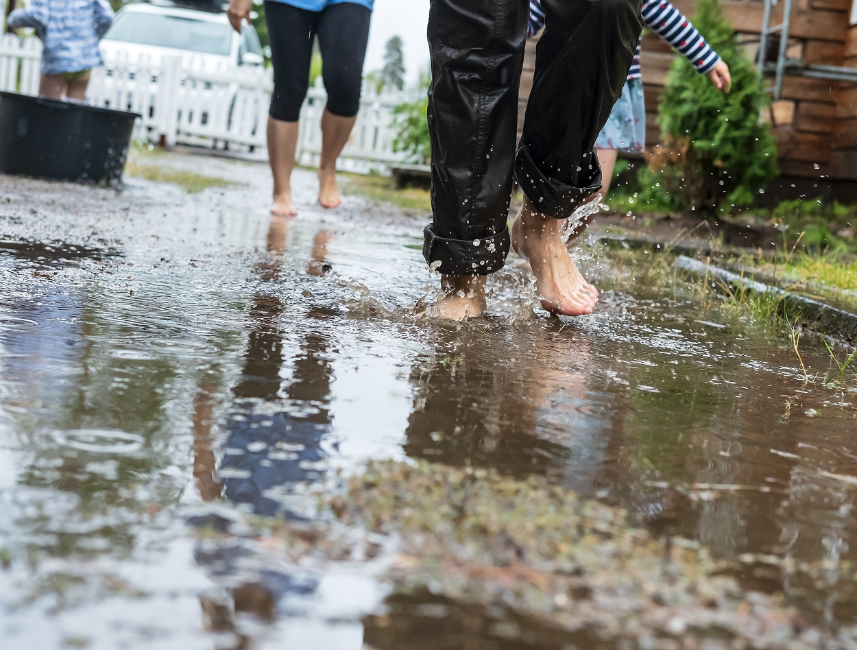 A family is walking through a puddle of water on a rainy day.