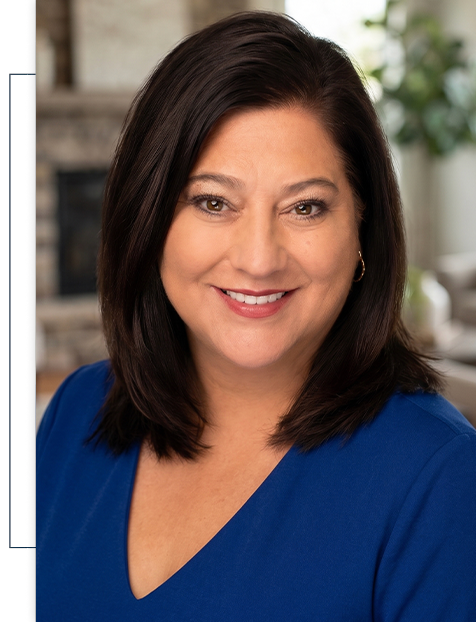 A woman in a blue shirt is smiling for the camera.