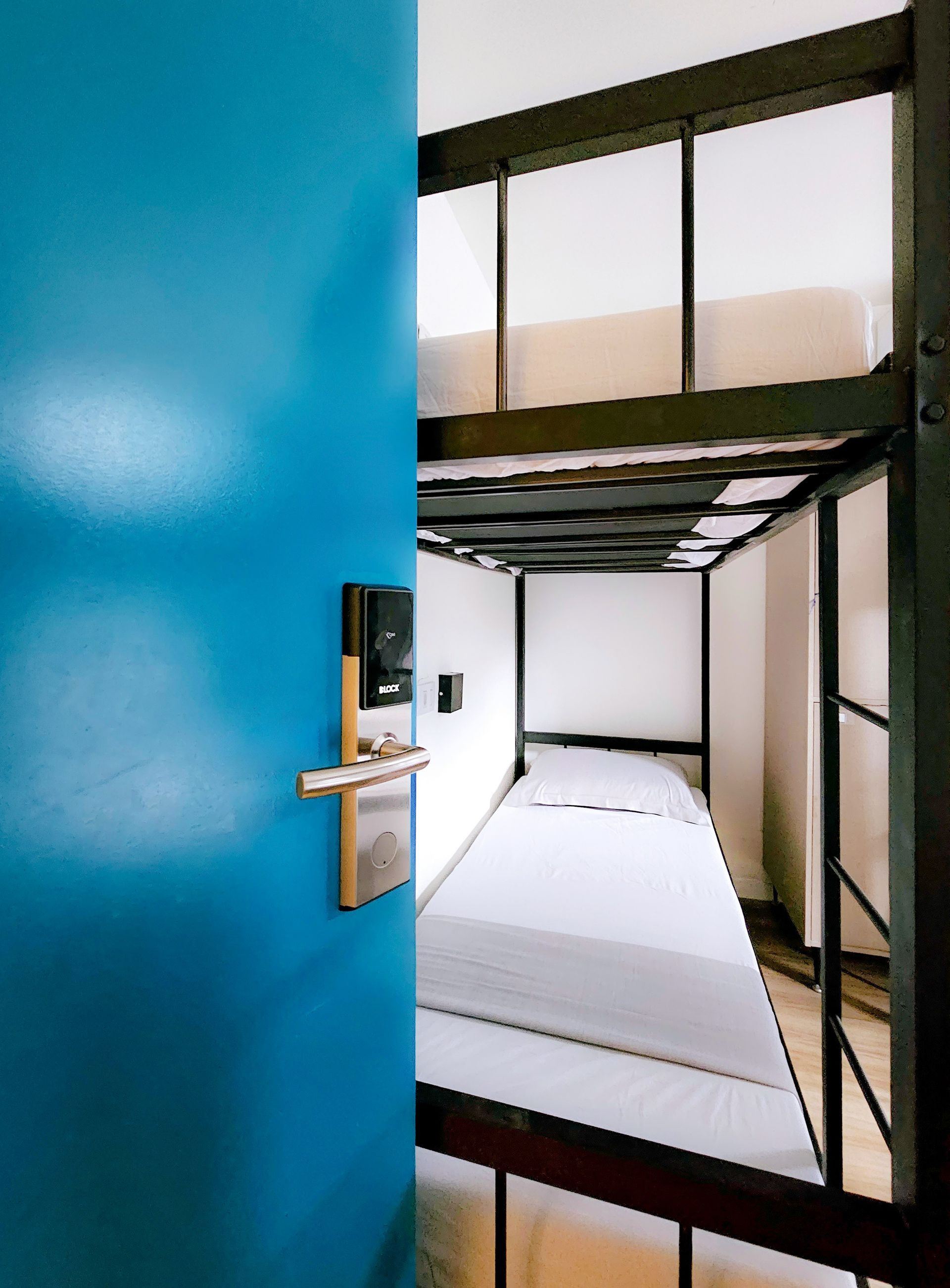 A bunk bed is behind a blue door in a room.