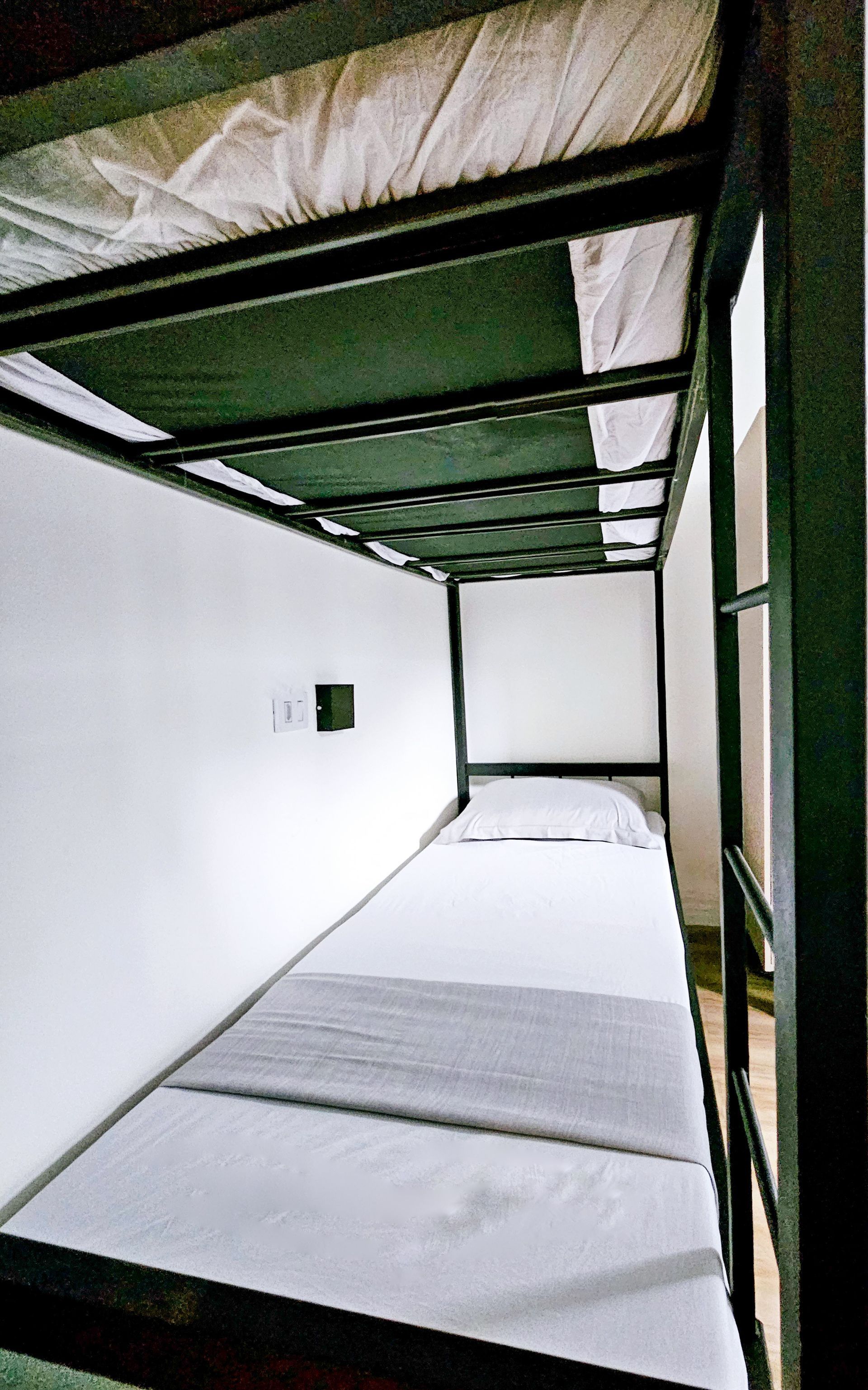 A bunk bed with white sheets and a black frame in a room.